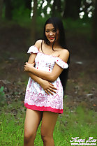 Standing in field arms folded under her chest wearing off the shoulder dress