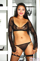 Keira Lee standing in front of shelves wearing sheer black lingerie in fishnet stockings