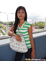 Overlooking busy road long hair over her shoulder wearing green striped top carrying bag
